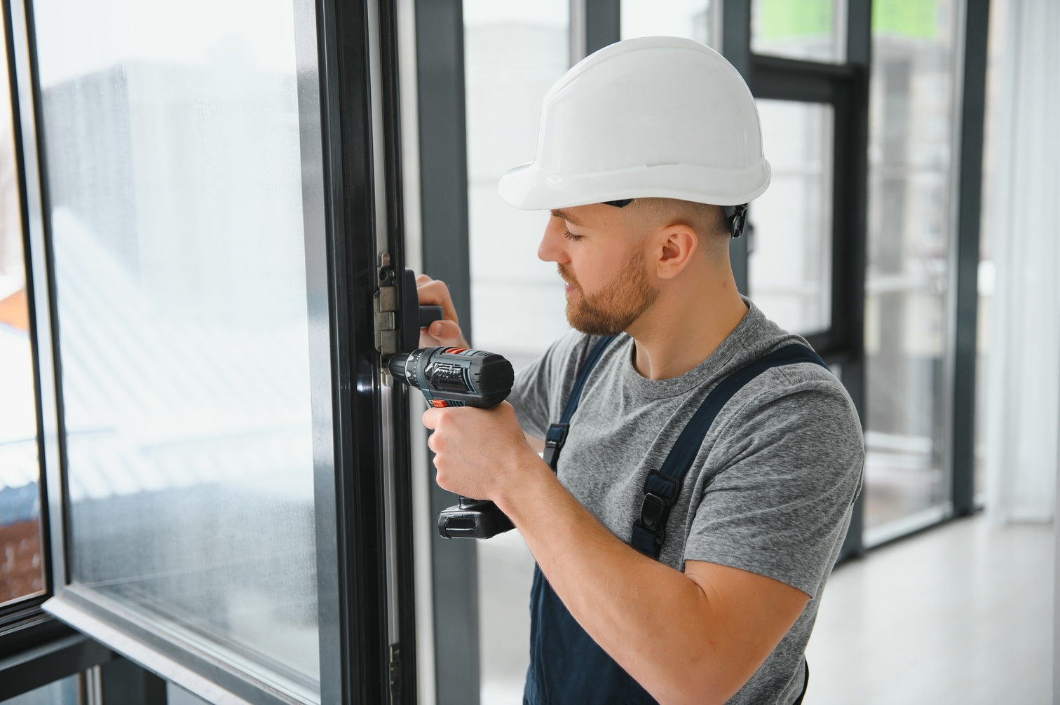 Construction worker using drill while installing window indoors services de châssis